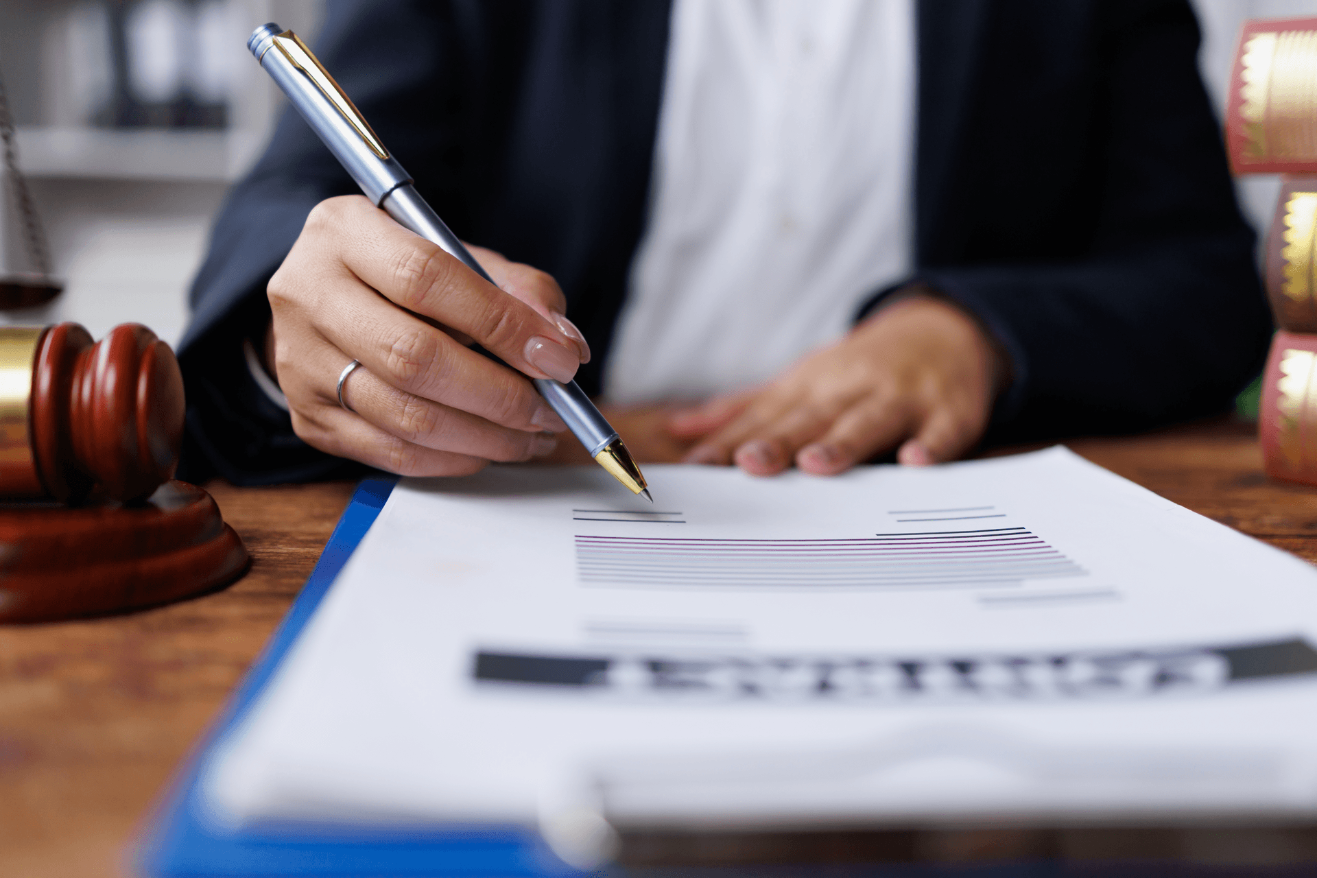Person signing a document beside a gavel